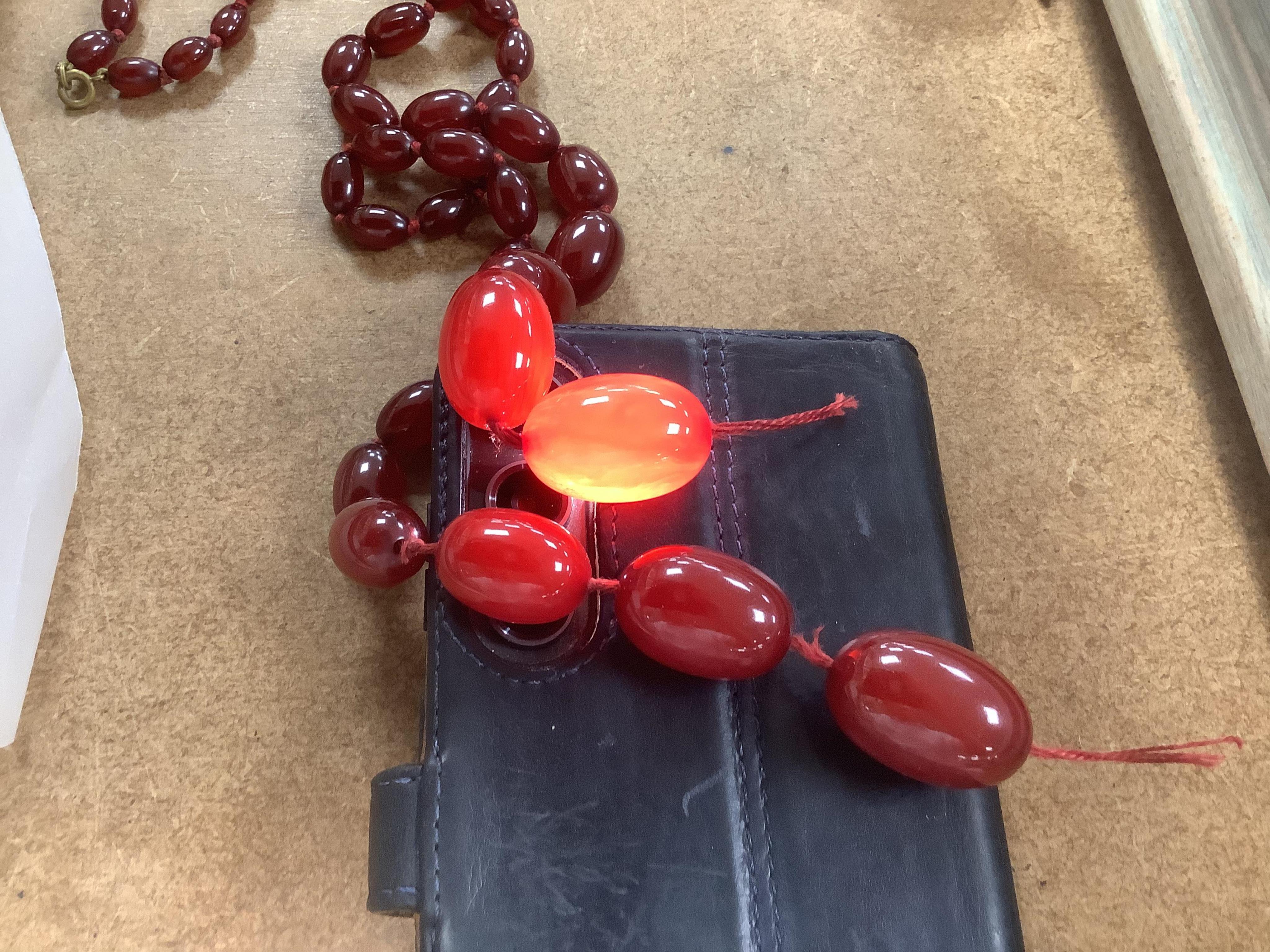 A single strand graduated simulated oval cherry amber bead necklace, string broken, gross weight 73 grams.